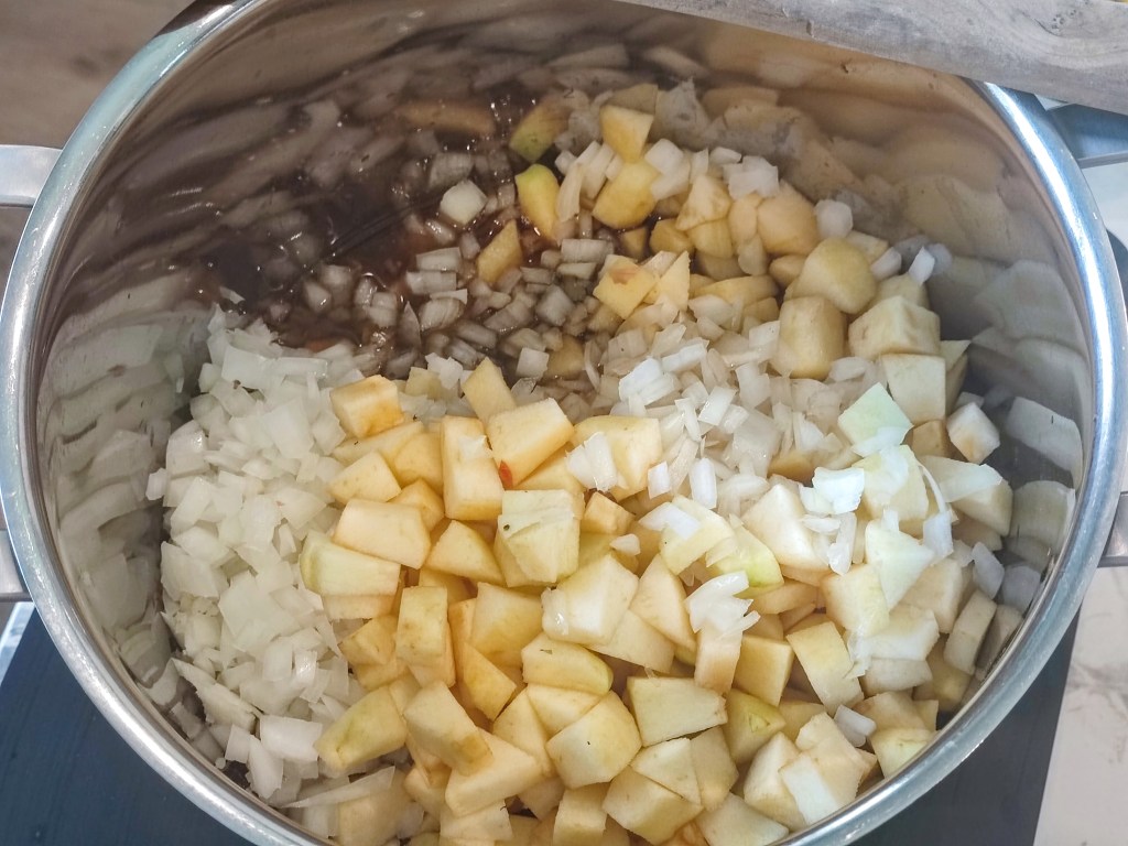 A pot filled with diced apples and chopped onions, ready for cooking.